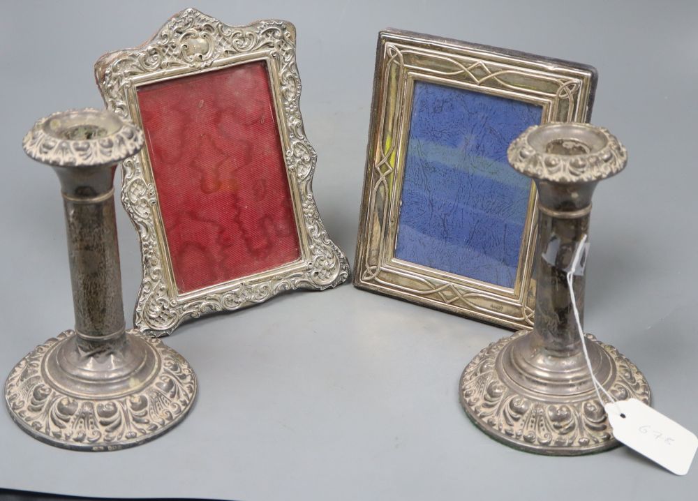 A pair of Edwardian silver candlesticks (a.f.), 17.3cm and two silver mounted photograph frames(a.f.).